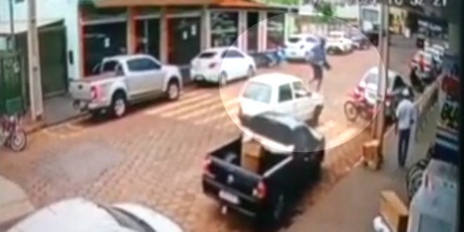 Homem sobe em capô de carro que parou em cima de faixa de pedestres para atravessar a rua